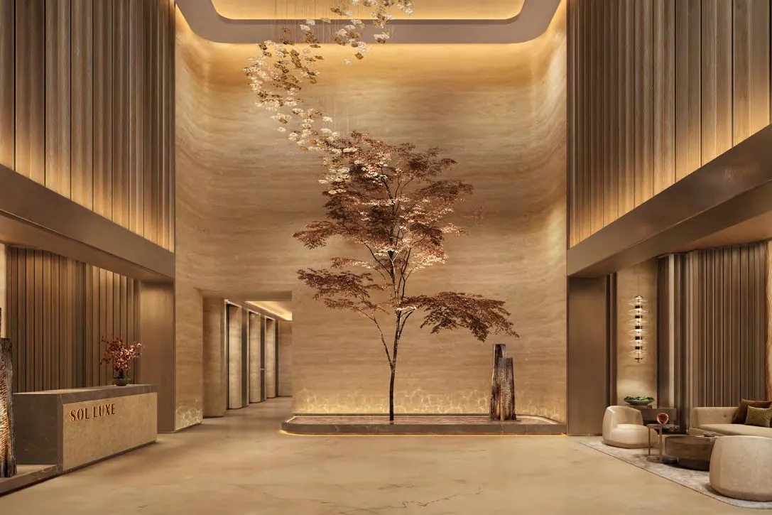 Double-height lobby in travertine and bronze with a sculptural tree